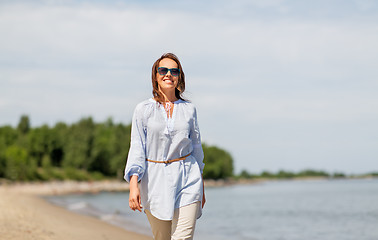 Image showing happy smiling woman walking along summer beach