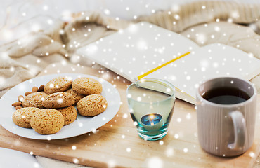 Image showing cookies, tea and candle at home over snow