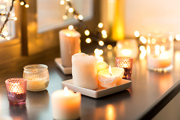 Image showing candles burning on window sill with garland lights