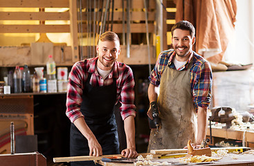 Image showing happy carpenters with drill and board at workshop