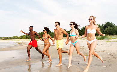 Image showing happy friends running on summer beach