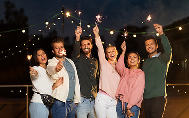 Image showing happy friends with sparklers at rooftop party