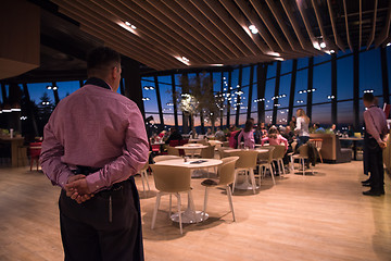 Image showing waiter standing with hands behind his back