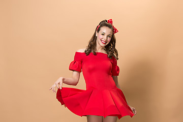 Image showing Beautiful young woman with pinup make-up and hairstyle. Studio shot on pastel background