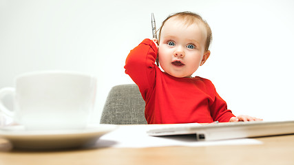 Image showing Happy child baby girl toddler sitting with keyboard of computer isolated on a white background