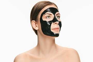 Image showing Young beautiful woman applying a mask for the face of the therapeutic black mud. Spa treatment