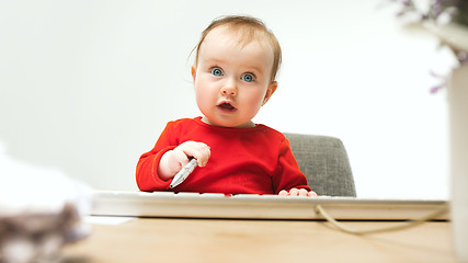 Image showing Happy child baby girl toddler sitting with keyboard of computer isolated on a white background