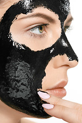 Image showing Young beautiful woman applying a mask for the face of the therapeutic black mud. Spa treatment