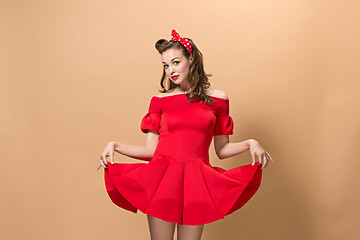 Image showing Beautiful young woman with pinup make-up and hairstyle. Studio shot on pastel background