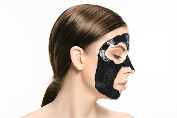 Image showing Young beautiful woman applying a mask for the face of the therapeutic black mud. Spa treatment