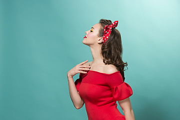 Image showing Beautiful young woman with pinup make-up and hairstyle. Studio shot on pastel background