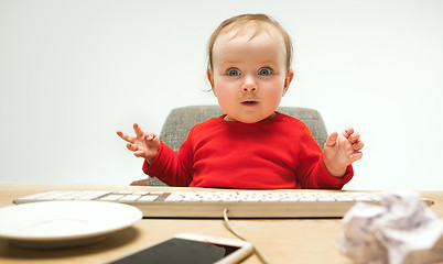 Image showing Happy child baby girl toddler sitting with keyboard of computer isolated on a white background