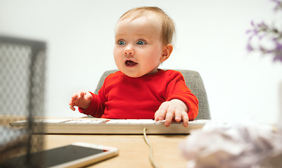 Image showing Happy child baby girl toddler sitting with keyboard of computer isolated on a white background