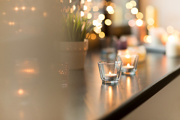 Image showing candles burning on window sill with garland lights