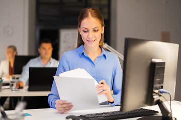 Image showing businesswoman with papers working at night office