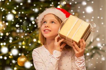 Image showing smiling girl in santa hat with christmas gift