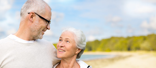 Image showing happy senior couple hugging over beach background