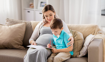 Image showing pregnant mother and son with workbook at home