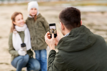 Image showing family photographing by smartphone on autumn beach