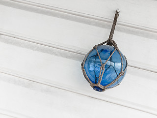 Image showing Blue glass ball decorating a white wooden wall