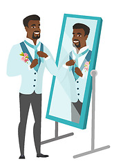 Image showing Groom looking in the mirror and adjusting tie.