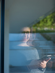 Image showing Woman using tablet at home by the window