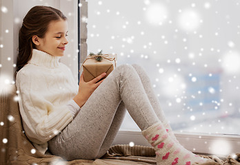 Image showing girl with christmas gift sitting on sill at home