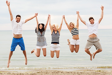 Image showing friends in striped clothes running along beach