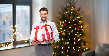 Image showing happy man with christmas gifts at home