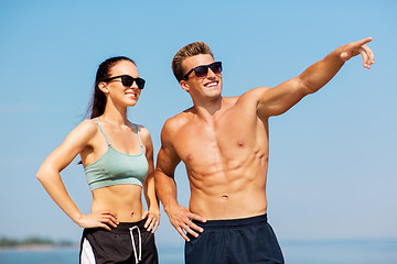 Image showing happy couple in sports clothes and shades on beach