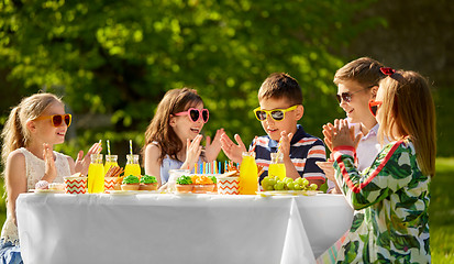 Image showing happy kids with cake on birthday party in summer