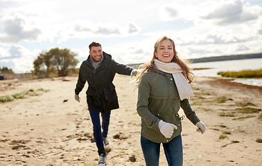 Image showing couple running along autumn beach