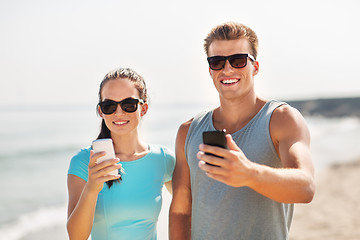Image showing couple in sports clothes with smartphones on beach