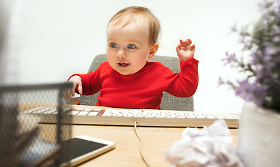 Image showing Happy child baby girl toddler sitting with keyboard of computer isolated on a white background