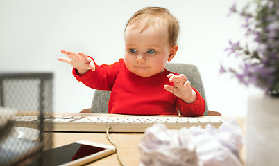 Image showing Happy child baby girl toddler sitting with keyboard of computer isolated on a white background