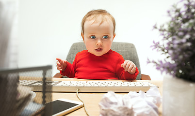 Image showing Happy child baby girl toddler sitting with keyboard of computer isolated on a white background