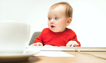 Image showing Happy child baby girl toddler sitting with keyboard of computer isolated on a white background