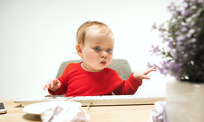 Image showing Happy child baby girl toddler sitting with keyboard of computer isolated on a white background