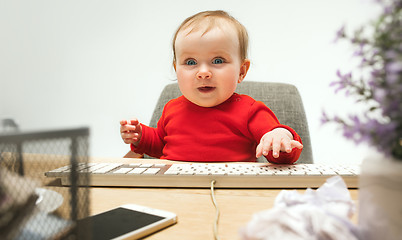 Image showing Happy child baby girl toddler sitting with keyboard of computer isolated on a white background