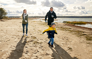 Image showing happy family running along autumn beach