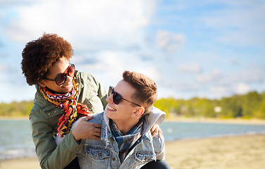 Image showing happy teenage couple in shades having fun on beach