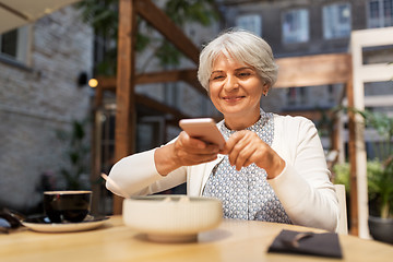 Image showing senior woman photographing food at street cafe