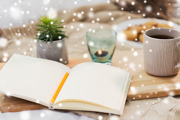 Image showing diary, tea and candle in holder at home over snow