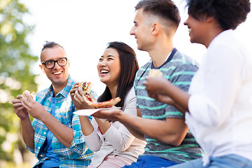 Image showing happy friends eating sandwiches and pizza outdoors