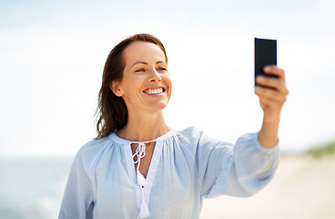 Image showing happy smiling woman taking selfie on summer beach