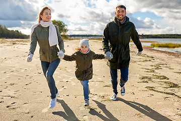 Image showing happy family running along autumn beach