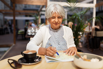 Image showing senior woman with map and coffee at street cafe