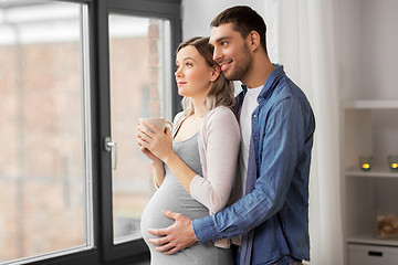 Image showing man hugging pregnant woman at window at home