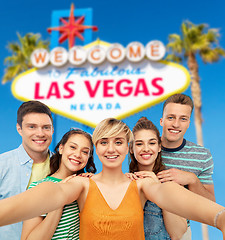 Image showing happy friends taking selfie over las vegas sign