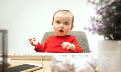 Image showing Happy child baby girl toddler sitting with keyboard of computer isolated on a white background